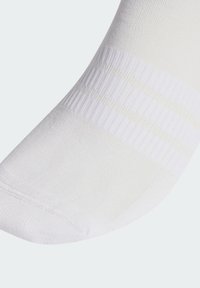 Bijela sportska čarapa s rebrastom teksturom, s pojačanim dijelovima na prstima i peti. Suptilni prugasti uzorak blizu vrha za dodatni detalj.