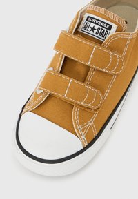 Κοντό αθλητικό παπούτσι Converse All Star σε μουσταρδί κίτρινο με λευκή λαστιχένια μύτη και δύο ιμάντες με βέλκρο.