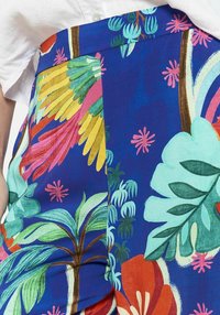 Barvita tropska krila z živahno modro podlago in zelenimi, rumenimi, roza in rdečimi cvetličnimi vzorci, izdelana iz lahkotnega blaga.