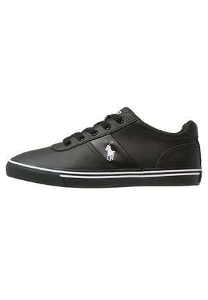 Zwarte leren lage sneaker met zwarte veters, witte zoolstrepen en een wit Polo-logo aan de zijkant.