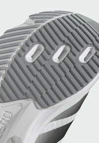 Szürke gumis sneaker talp, texturált barázdákkal, három perforációval és fehér díszítéssel a széleken.