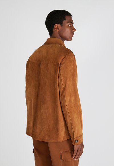 Braune Wildlederjacke mit strukturiertem Finish, ausgestattet mit einem geknöpften Bündchen und einem geraden Saum. Das Design ist schlicht, mit minimalen Nähdetails.