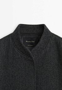 Manteau en laine gris foncé avec col montant, design minimaliste et texture lisse, étiqueté "Massimo Dutti". Fabriqué au Maroc.
