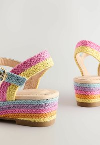 Tkané platformové sandály s multibarevnými pletenými pásky v růžové, žluté, modré a fialové barvě, s světlou béžovou stélkou a pevným podkladem.