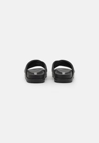 Svarta slide-sandaler i slät syntetisk material med öppen tå-design och tjock, dämpad sula för komfort.