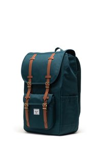 Teal canvas ryggsäck med två bruna läderremmar, gulddetaljer, en framficka och nätpanel på baksidan för komfort.