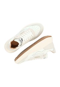 Zapatillas de cuero blancas con puntera perforada, acentos beige y suela de goma texturizada. Presentan un logo en la lengüeta y en el lateral.