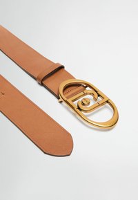 Tan læderbælte med en stor, oval guld spænde. Spændet har et logo og en glat overflade. Remmen er ensfarvet med en spidse ende.