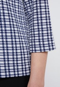 Marinblå och vit rutigt tyg med en mjuk textur, med kort ärm design och vävda mönster.