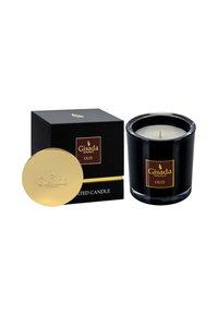 Schwarzes Glasgefäß mit einer weißen Wachsfüllung, goldenen Deckel und einer dekorativen schwarzen Schachtel mit goldenen und weißen Texten, beschriftet mit "Gisada Oud."