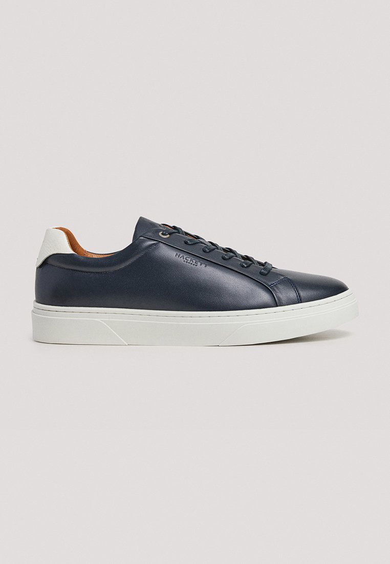 Baskets en cuir marine avec semelle en caoutchouc blanche, bout rond et talon beige contrasté. Dotées d'un système de laçage et d'un logo discret sur le côté.