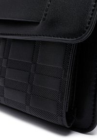 Borsa nera in pelle testurizzata, caratterizzata da un motivo intrecciato, design elegante e finiture lisce. La chiusura è a pattina con dettagli di cucitura.