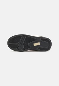 Semelle de sneaker en caoutchouc noir avec un motif de semelle texturé, un logo "Kappa" doré et un design de profil latéral lisse.