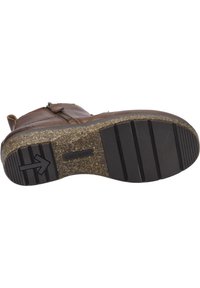 Brązowy skórzany but z teksturowaną podeszwą, z wyróżniającą się czarną prążkowaną gumową sekcją i detalem w kształcie strzałki. Zamek błyskawiczny po boku.