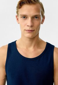Marineblauwe tanktop van katoen, met een ronde halslijn en brede schouderbanden. Gladde textuur met minimale stikseldetails.
