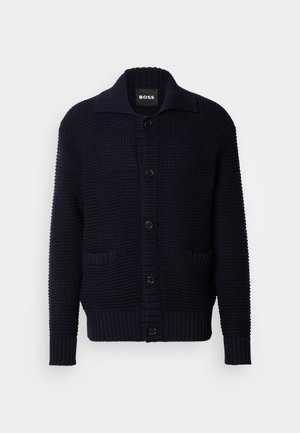 Navy knitted cardigan with large collar, button closure, and two front pockets; textured design with ribbed cuffs and hem.