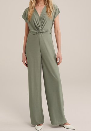 Combinaison vert olive avec un col en V profond et un détail torsadé à l'avant. Fabriquée en tissu doux et texturé, avec des jambes larges et des manches courtes.