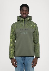 Sweatshirt com capuz em verde-oliva com um estampado texturizado em verde mais claro. Apresenta um fecho de correr de um quarto e um logótipo no peito. Tecido suave.