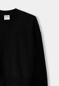 Sudadera negra con cuello redondo, con puños y dobladillo acanalados. Fabricada en una tela suave, exhibe un diseño simple y minimalista.