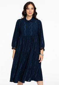 Dunkelblaues, gestuften Kleid aus strukturiertem Stoff mit Kragen, Knopfleiste und Spitzenakzenten an den Ärmeln. Verfügt über wellenförmige Ausschnittmuster.