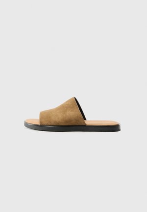 Sandale à brides en daim marron, avec une large sangle, semelle intérieure beige et semelle en caoutchouc noire, présentant une texture lisse et un design minimaliste.