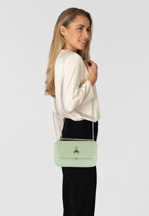 Borsa a spalla trapuntata verde chiaro con tracolla a catena e un emblema argento. Realizzata in materiale liscio, presenta una forma rettangolare e una chiusura a pattina.