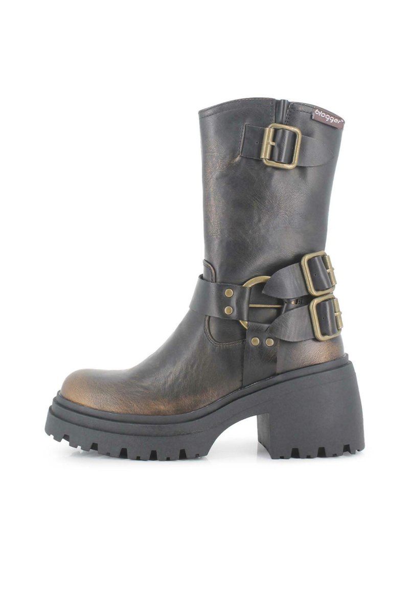 Bota de cuero negro hasta la rodilla con acentos metálicos, suela de goma gruesa y dos hebillas laterales. Presenta una puntera redonda y acabado texturizado.