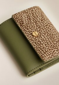 Portafoglio compatto con base in pelle verde oliva e pattina beige strutturata con piccoli punti marroni, chiuso da un bottone rotondo dorato.