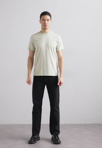 Hele roheline lühikeste varrukatega t-särk, mis on koos mustade pükstega, koos lihtsa disaini ja siledaks tekstuuriga. Minimalistlik välimus, ilma nähtavate mustriteta.