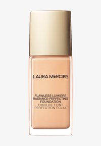 Fond de teint Flawless Lumière dans un flacon en verre beige avec un capuchon doré. Présente du texte noir pour les détails du produit et une base carrée.