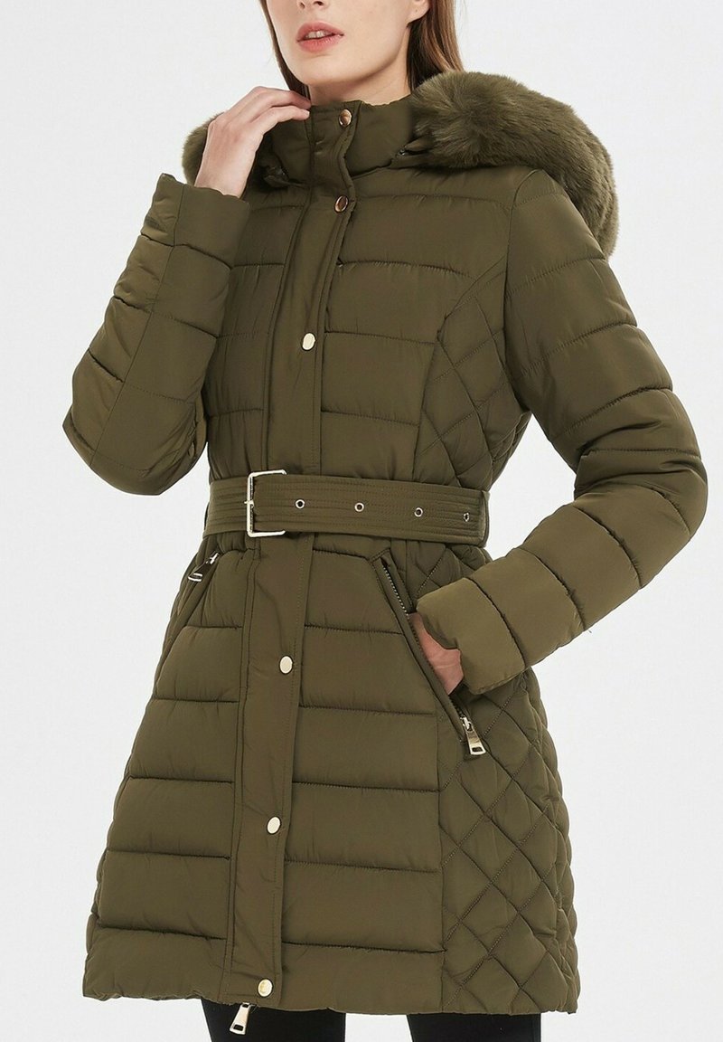 Doudoune verte olive avec une taille ceinturée, capuche en fausse fourrure et motif matelassé. Comprend des poches zippées et un col haut.