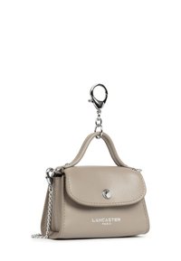 Piccolo portachiavi in pelle beige Lancaster Paris con patta, bottone argento, manico superiore e chiusura a catena su sfondo bianco.