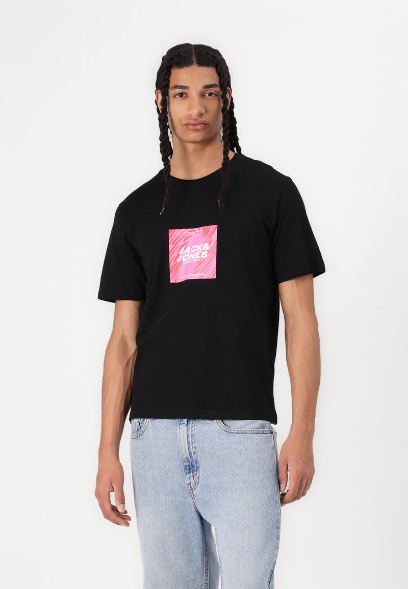 Musta puuvillapaita, jossa on keskeinen vaaleanpunainen grafiikka ja "JACK & JONES" -teksti, pyöreä kaula-aukko ja lyhyet hihat. Rentomallinen.