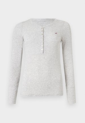 Camisola cinza de mangas longas feita de tecido canelado, com um gola Henley abotoada e um pequeno logótipo bordado no peito.