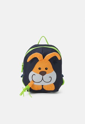 Sac à dos pour enfants bleu marine avec fermeture éclair et poignée vertes, arborant un visage de chien orange et blanc avec des oreilles tombantes et une patte tenant des cordons verts.