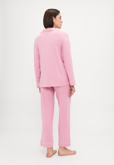Light pink pajamas made of soft fabric, featuring a button-up shirt with a collar and matching pants with cuffed hems.