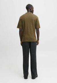 Olivgrön polo med geometrisk textur, korta ärmar och krage, kombinerad med mörkgrå raka byxor och svarta skor.