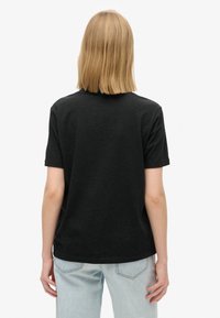T-shirt noir à manches courtes avec un col rond. Matière en mélange de coton. Vue arrière montrant une coupe décontractée et un design minimaliste.