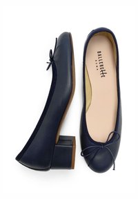 Ballerine in pelle blu navy con un piccolo tacco a blocco, punta rotonda e un fiocco decorativo nella parte anteriore. L'interno è foderato in beige.