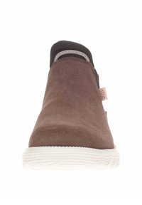 Scarpa slip-on in suede marrone con bordi in tessuto nero, punta arrotondata e suola in gomma bianca testurizzata. Presenta cuciture minime e un'etichetta laterale.