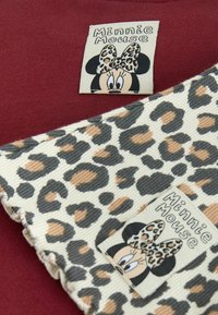 Minnie-Maus-Etiketten auf burgunderrotem Stoff und Cord aus Leopardenmuster, mit strukturierten Designs in Beige, Braun und Schwarz, versehen mit charakteristischen Schleifendetails.