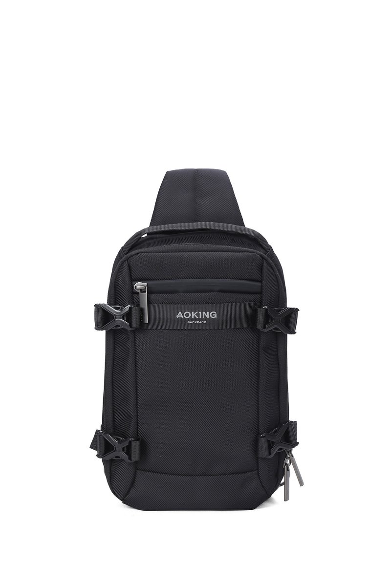 Zaino a spalla in tessuto nero con spallacci regolabili, tasche con zip esterne e fibbie laterali. Presenta il logo sul pannello frontale.
