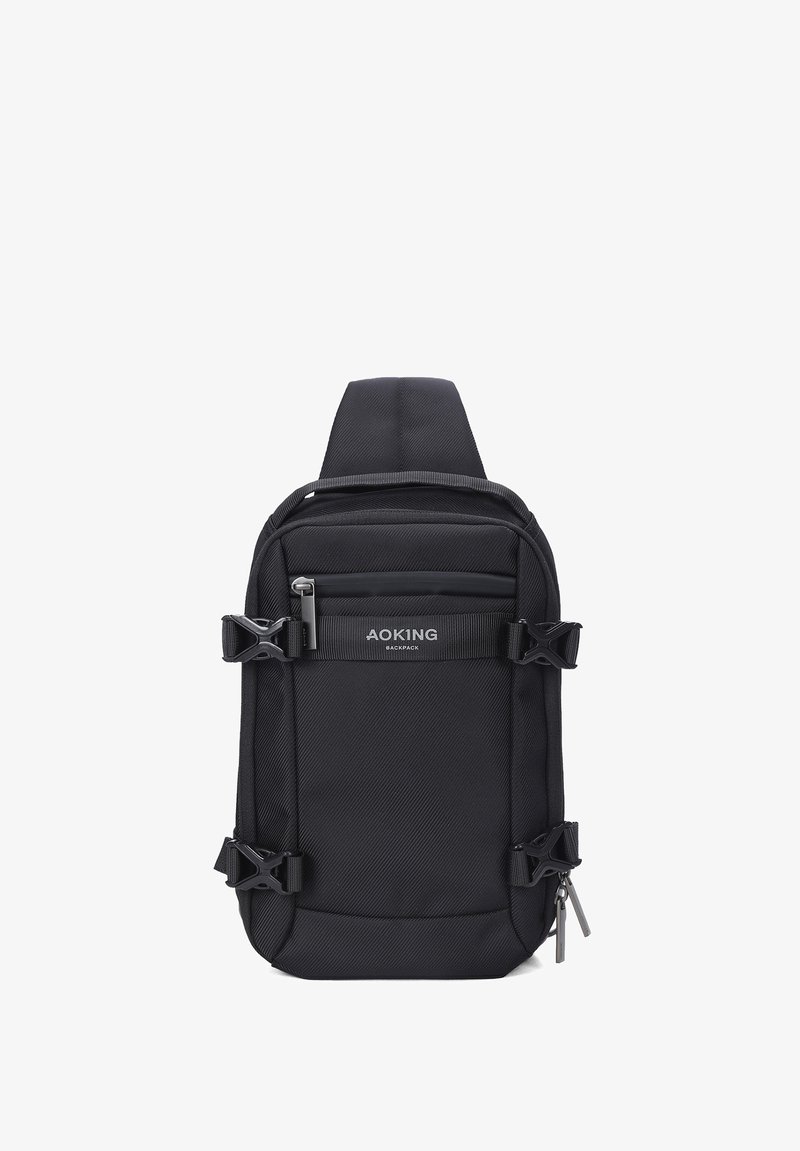 Zaino a spalla in tessuto nero con spallacci regolabili, tasche con zip esterne e fibbie laterali. Presenta il logo sul pannello frontale.