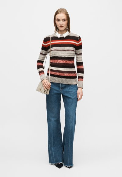 Knitted sweater with horizontal stripes in brown, red, and beige; paired with high-waisted blue jeans and a small gray handbag.
