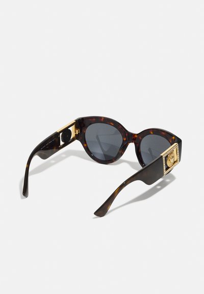 Ochelari de soare din material tortoiseshell cu formă de ochi de pisică, accente aurii pe temple, lentile gri închis și un detaliu texturat la balama.