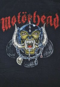 Sort t-shirt med et detaljeret grafisk motiv af et kranium med horn, et pigget hjelm og kæder. Ordet "Motörhead" er trykt i rødt ovenfor.