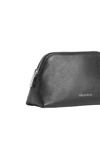 Pochette en cuir noir avec une finition texturée, une partie supérieure arrondie et une fermeture éclair argentée. Présente un logo embossé subtil sur le côté.