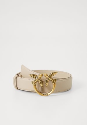 Beige leren riem met een ronde goudkleurige gesp versierd met twee vogelaccenten, gedetailleerd met zwarte patronen.