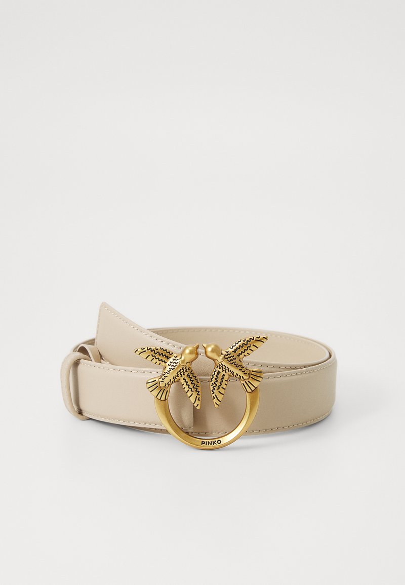 Cintura in pelle beige con fibbia rotonda in tono oro decorata con due accenti di uccelli, dettagliata con motivi neri.