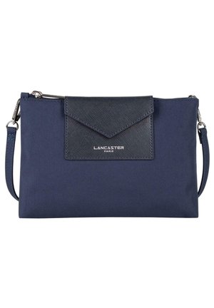Sac en tissu bleu marine avec un rabat texturé bleu foncé. Équipé d'une fermeture éclaire argentée et du logo "Lancaster Paris" à l'avant. Comprend une bandoulière.